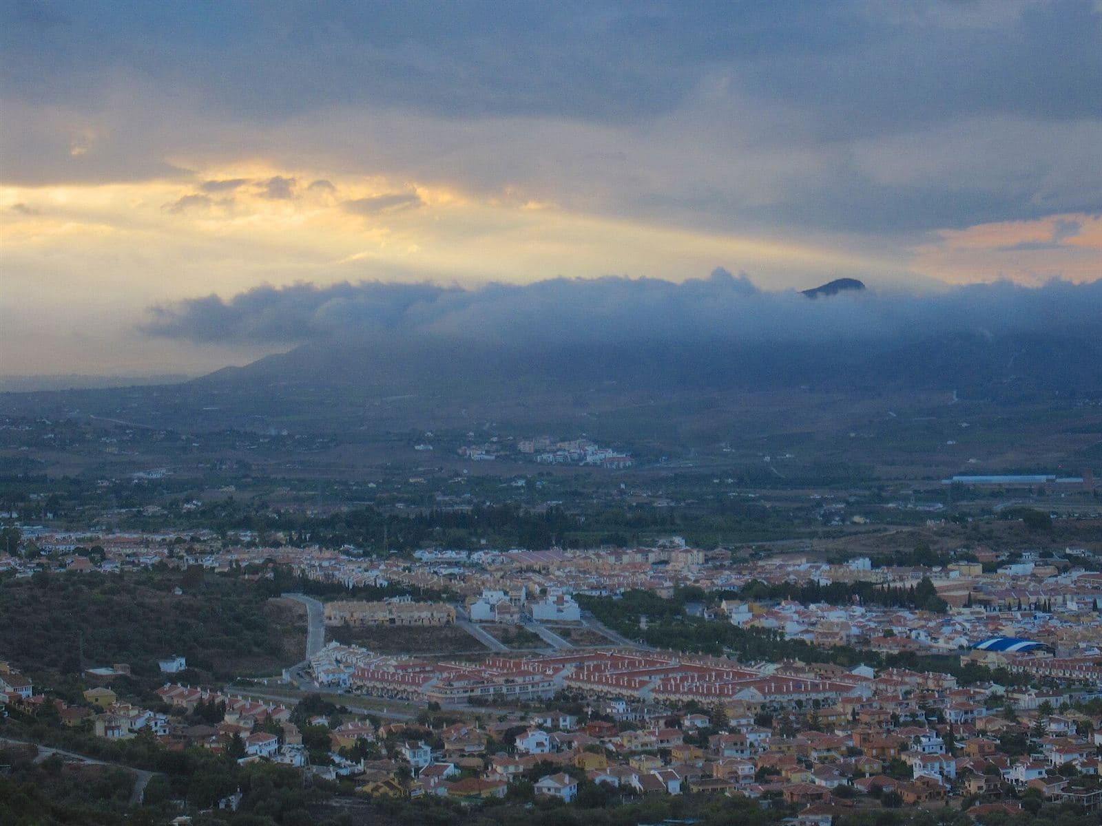Alhaurín de la Torre at dusk, the town spread across the valley floor below the Sierra de Mijas