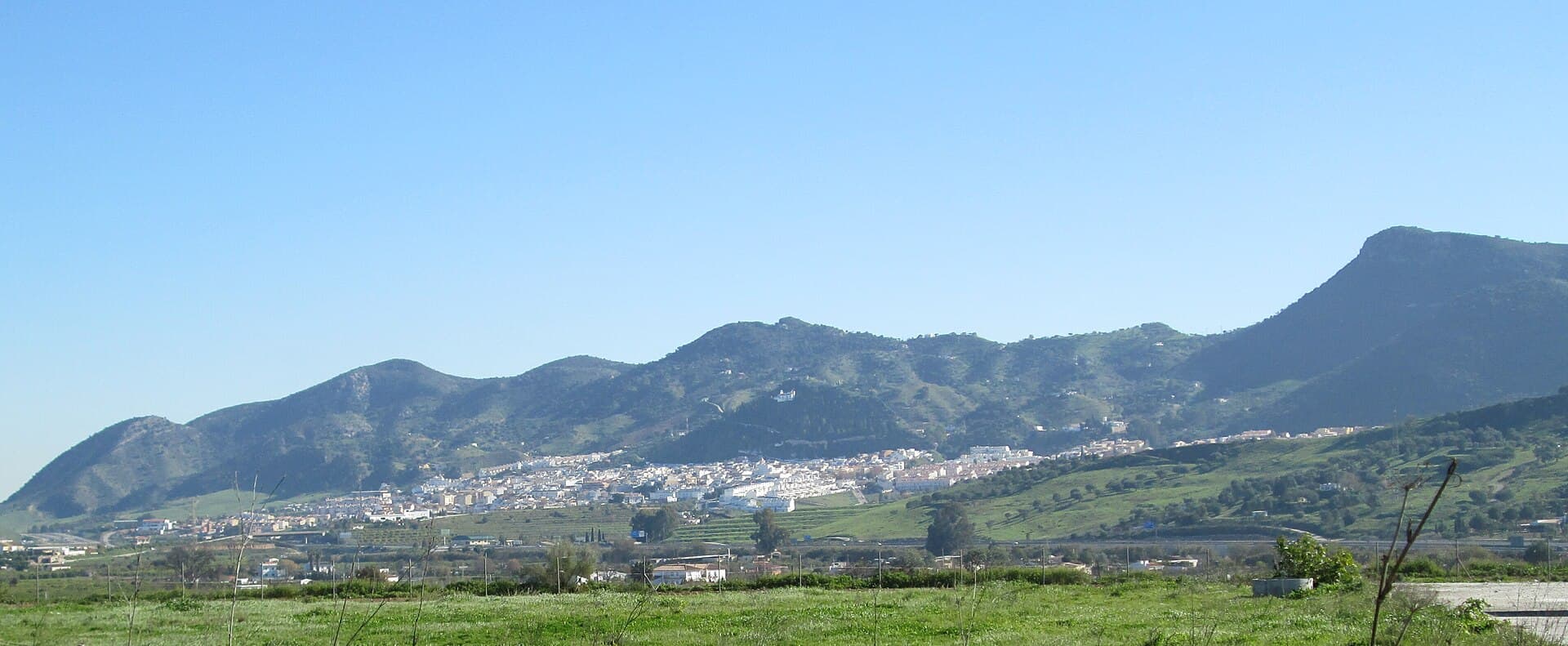 Cártama pueblo, white houses along the hillside under the sierra, seen across the Guadalhorce valley