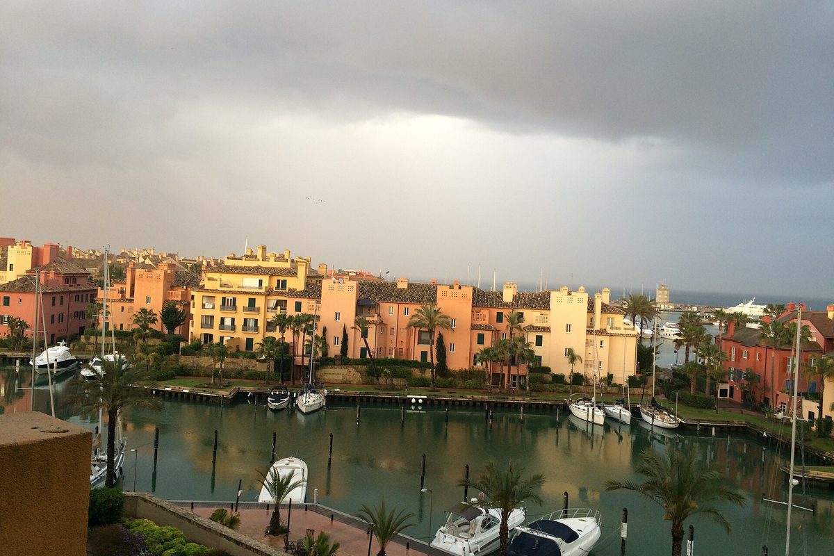 The marina and its terracotta apartments under a storm sky