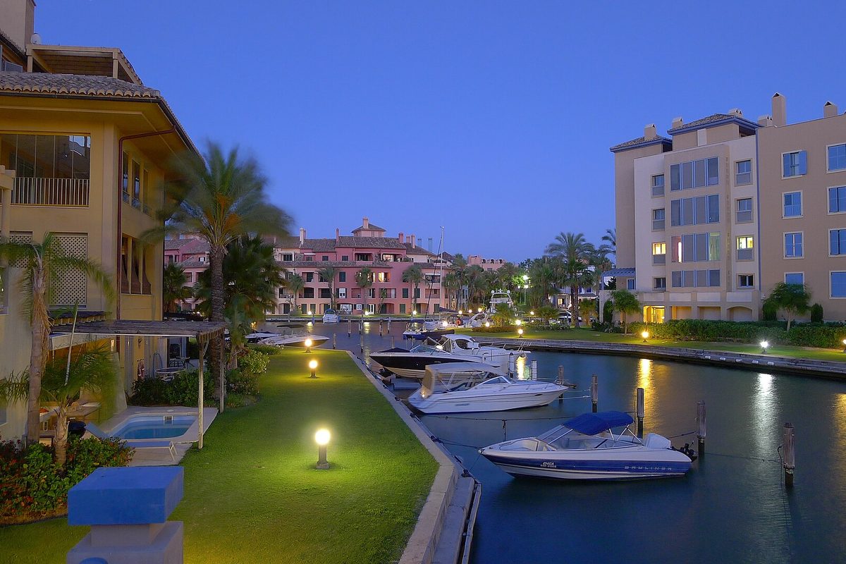 A canal in the marina at dusk, lamps lit along the lawns
