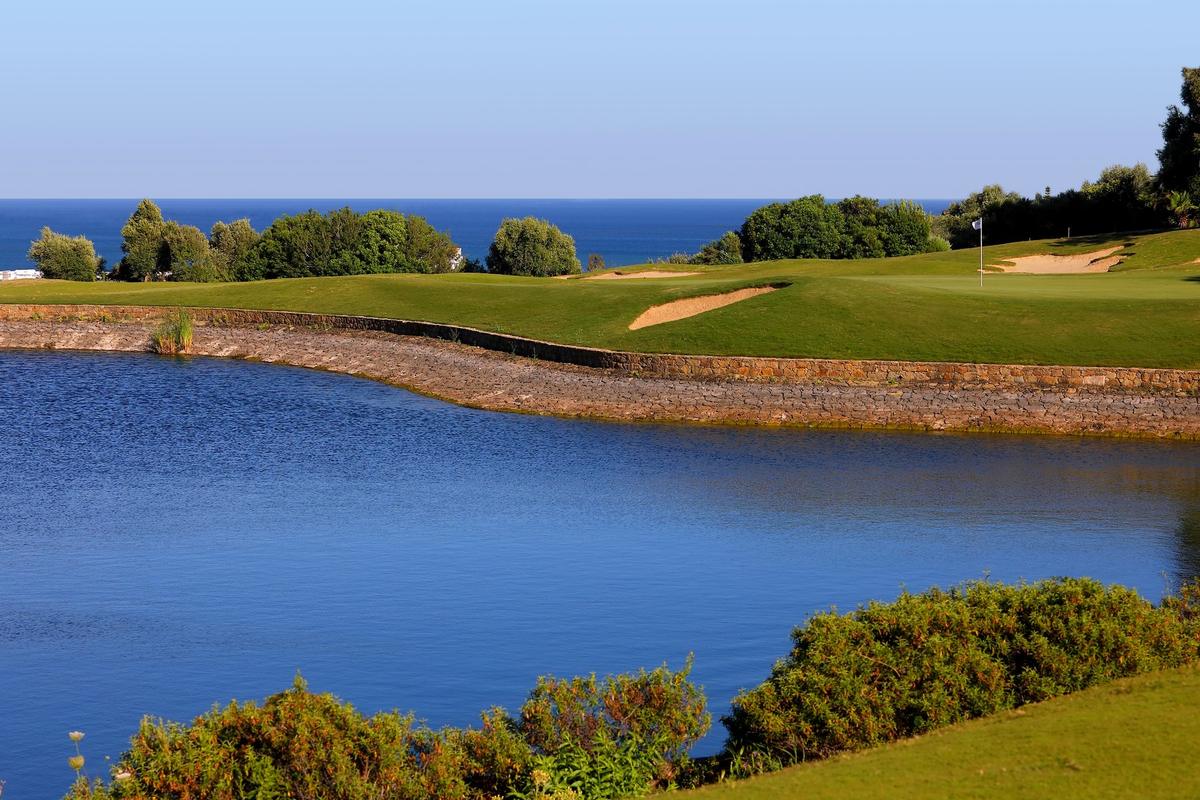 Hole 14 across the water, with the sea beyond
